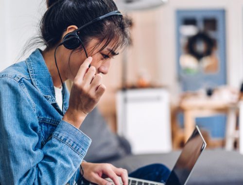 Young smiling happy beautiful asian woman relaxing using laptop computer working and video conference meeting at home.Young creative girl talk with headset.work from home concept